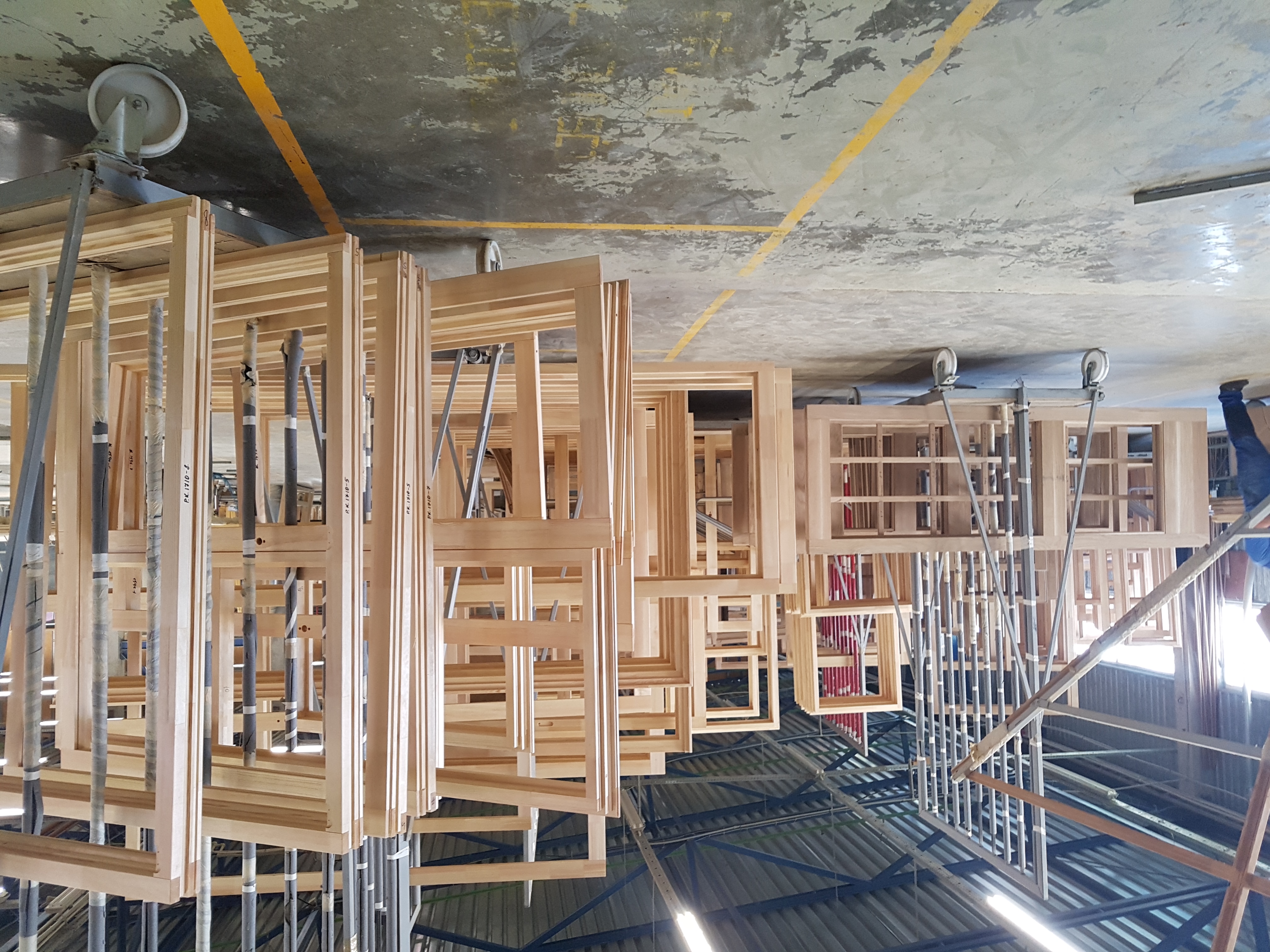 Houten kozijn-frames hangend in de Doleta fabriek tijdens lak- of droogfase